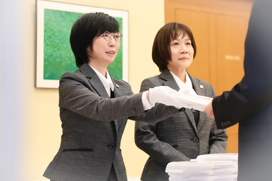 めがねの女性スタッフが丁寧に品物をお渡ししている様子