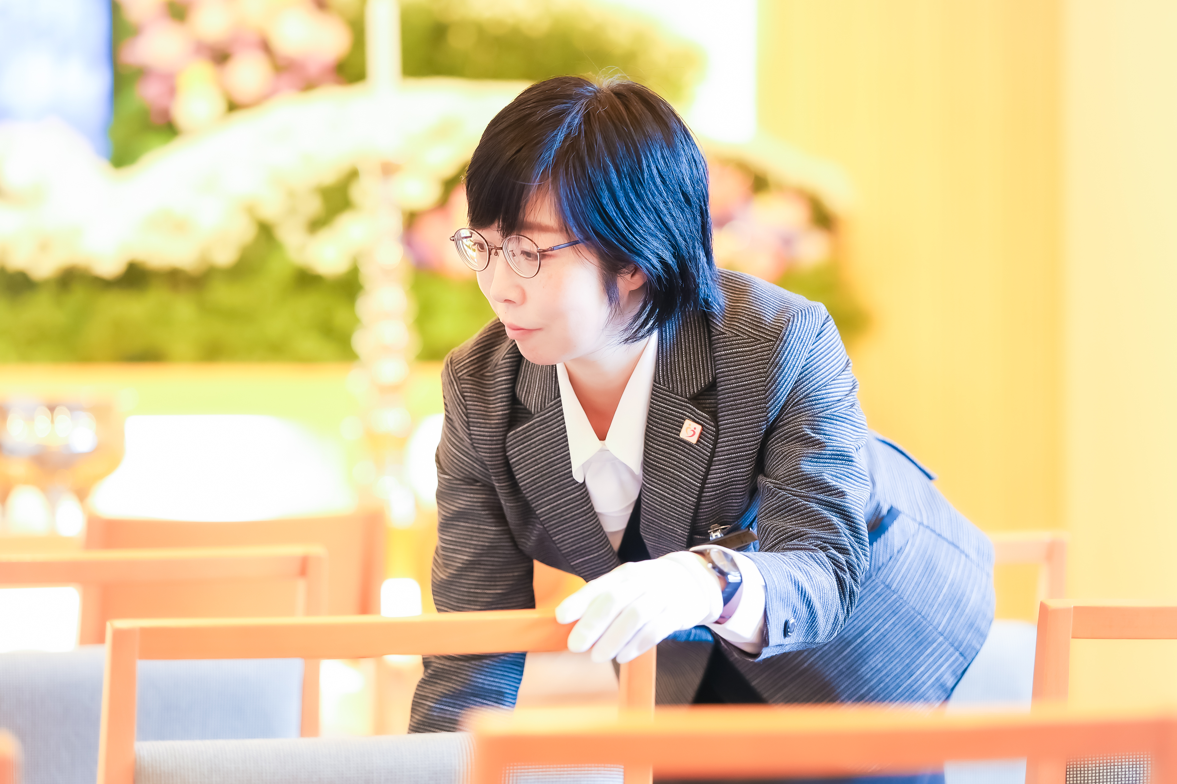 椅子を整えるめがねの女性スタッフ